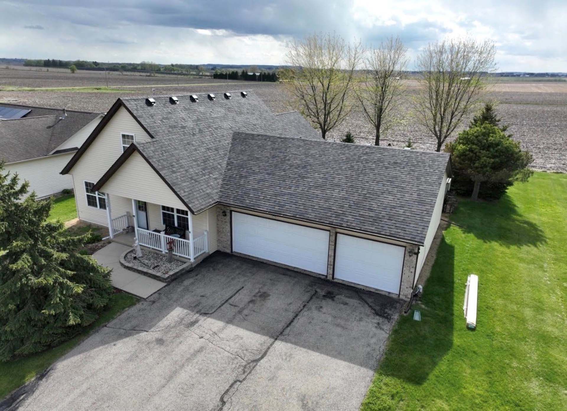 Suburban house with two-car garage, driveway, and front porch under cloudy sky
