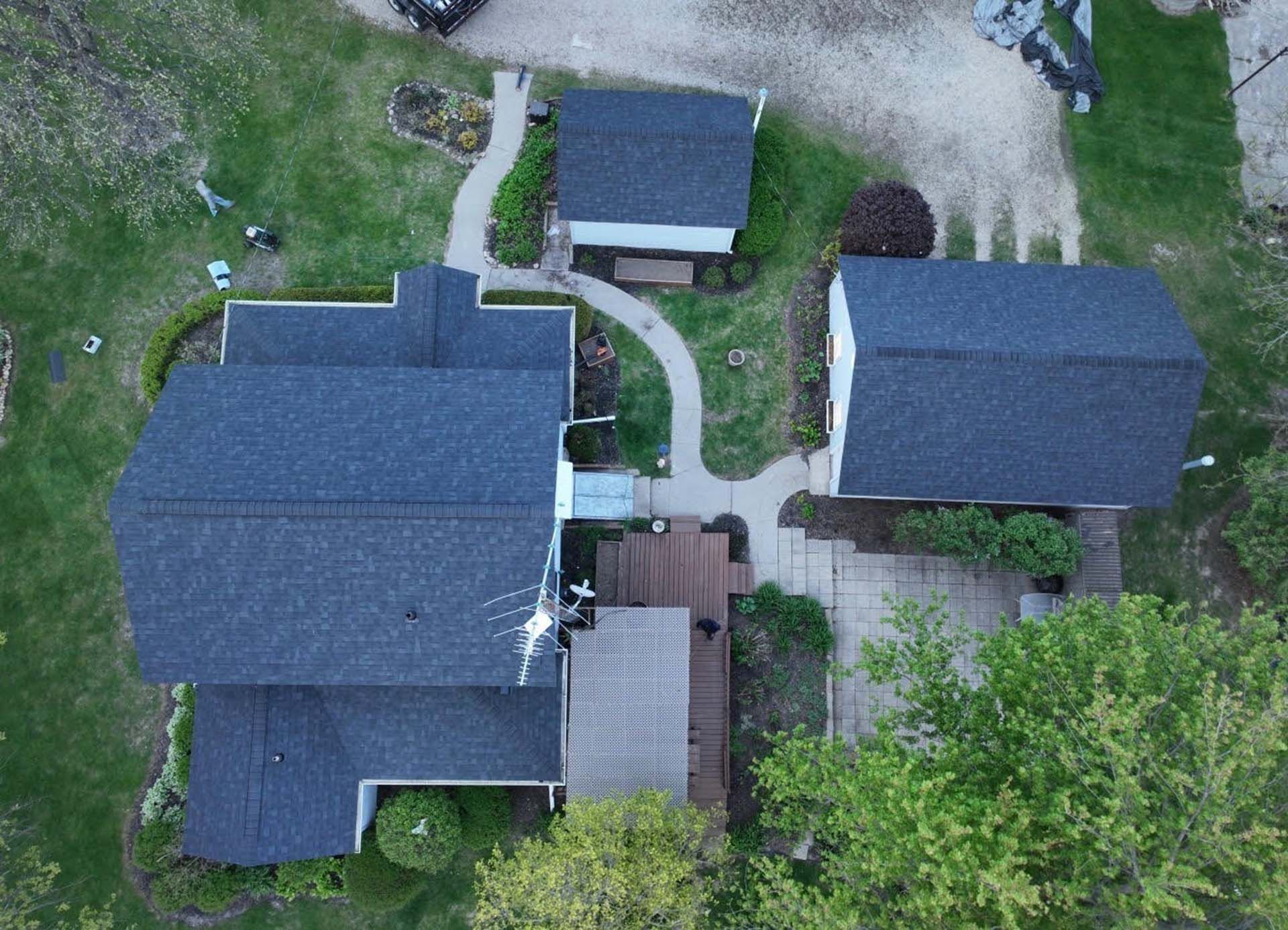 Aerial view of three dark-roofed buildings connected by walkways and surrounded by grass