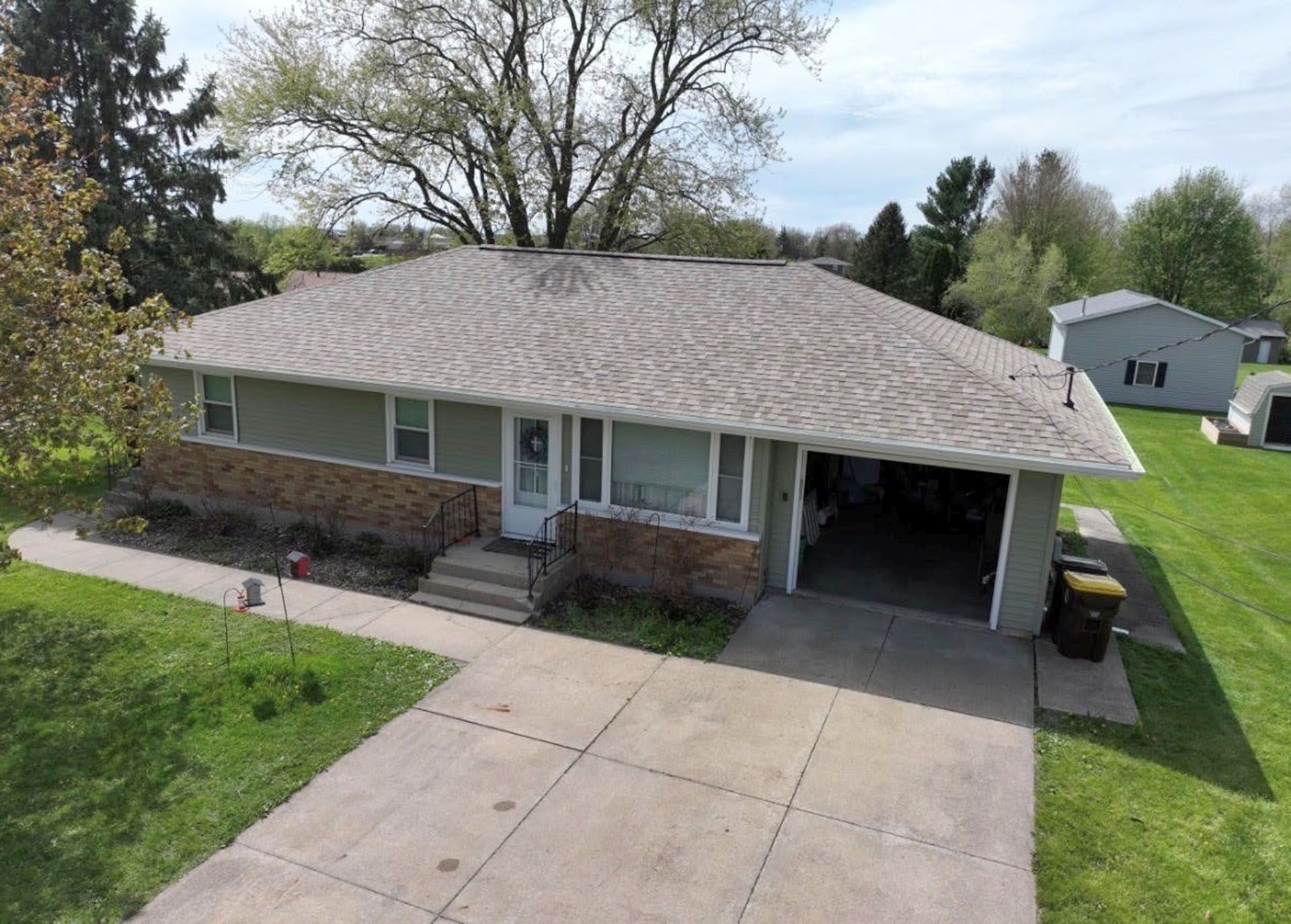 Single-story brick house with driveway, front porch, and carport in a suburban yard