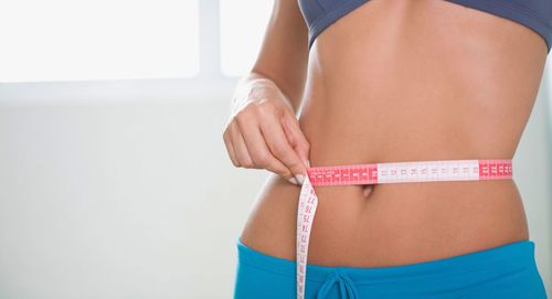 Measuring tape around a slim waist with a pink and white tape