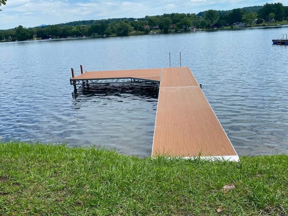 Wooden dock extending into a calm lake, with grassy shoreline in the foreground.