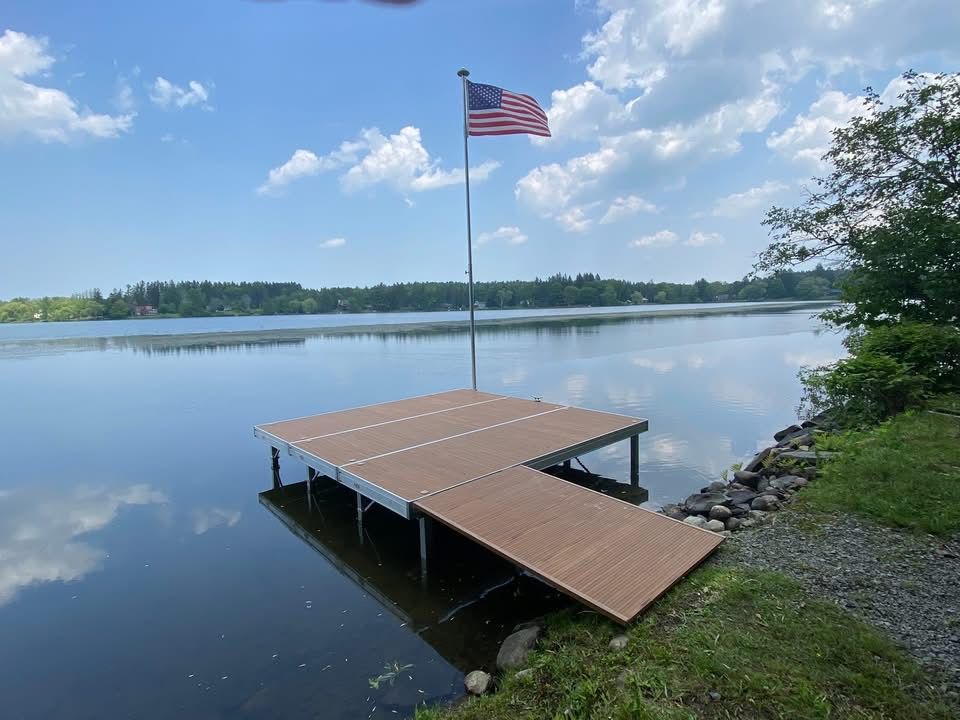 Wooden dock on a calm lake with an American flag under a blue sky
