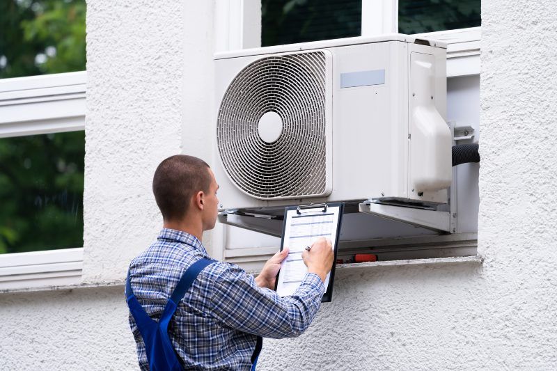 Technician Examing Outdoor AC Unit in Volusia & Flagler Counties, FL