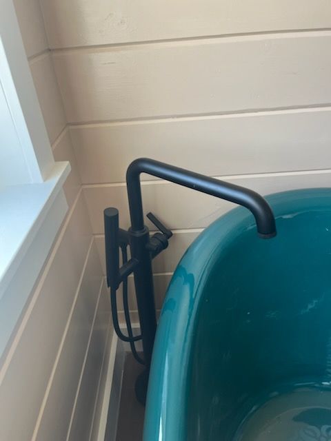 A blue bathtub with a black faucet in a bathroom.