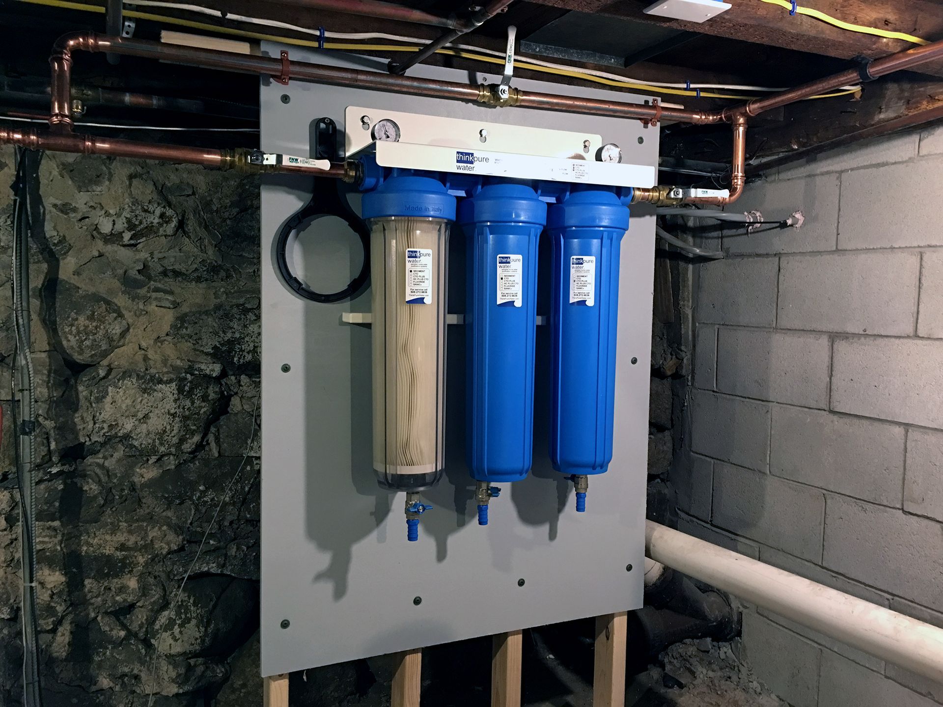 A water filter is mounted to a wall in a basement