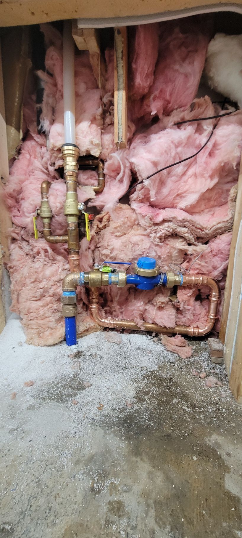 A water meter is sitting in a hole in the wall.