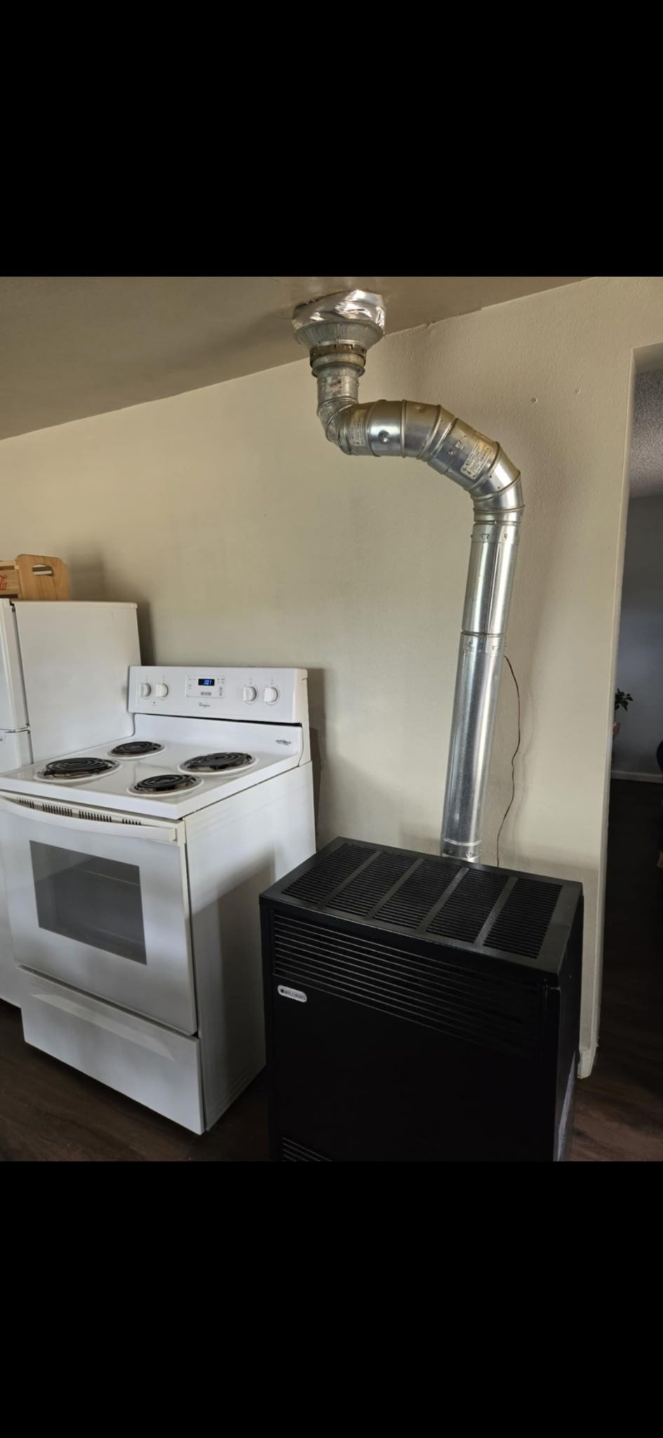 A stove with a chimney attached to it is in a kitchen.