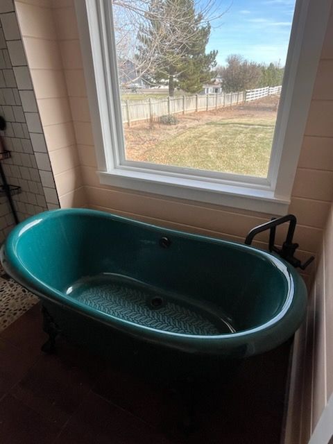 A green bathtub is sitting in a bathroom next to a window.