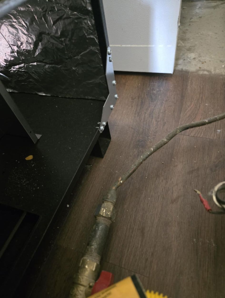 A close up of a pipe on a wooden floor next to a washer and dryer.