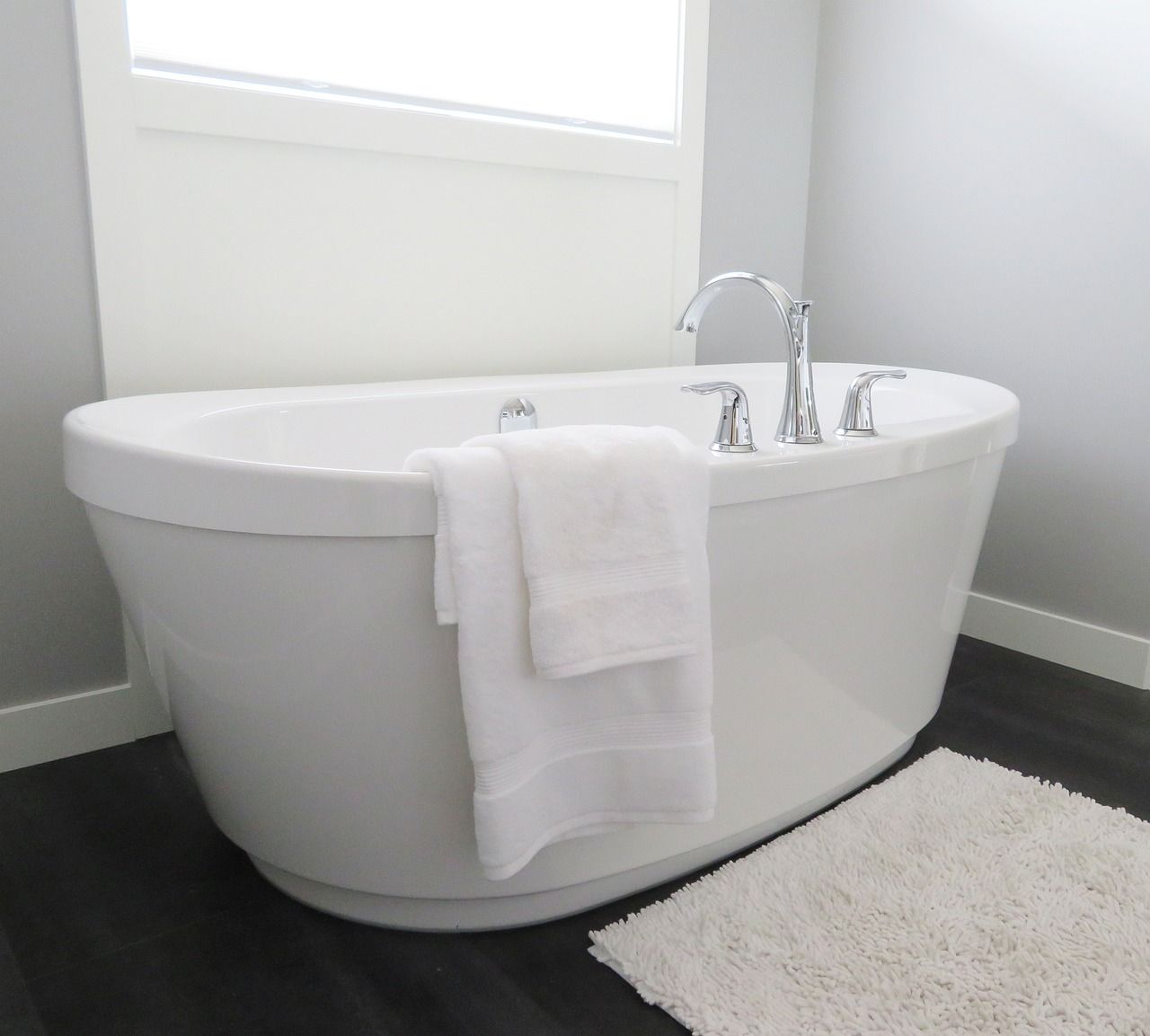 A white bathtub in a bathroom next to a window.