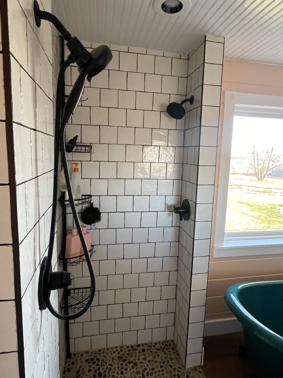 A bathroom with white tiles and a green tub