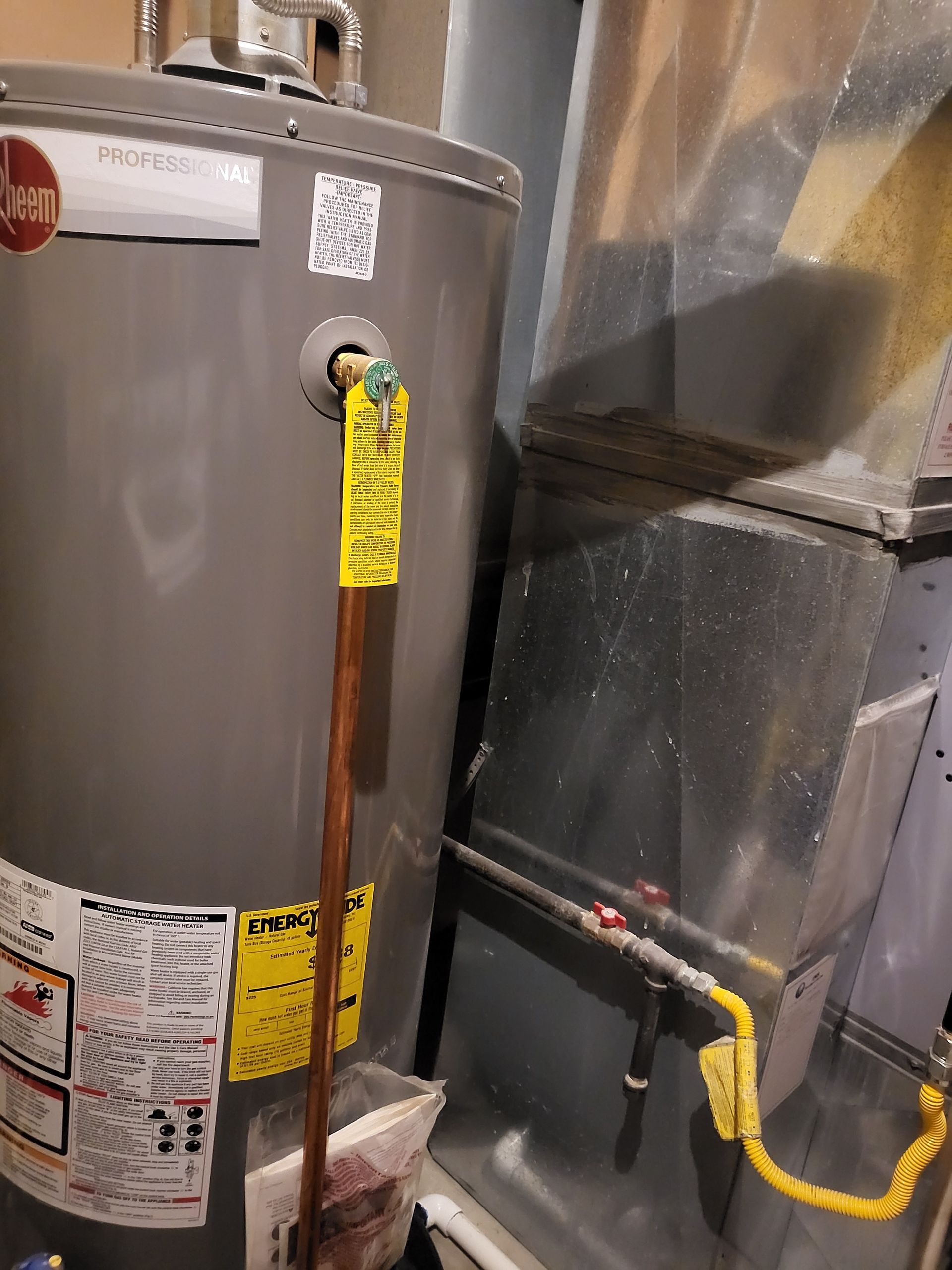 A gray water heater with a yellow tag on it