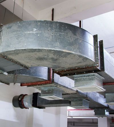 Exposed industrial galvanized steel HVAC ductwork with rectangular vents attached to the ceiling.