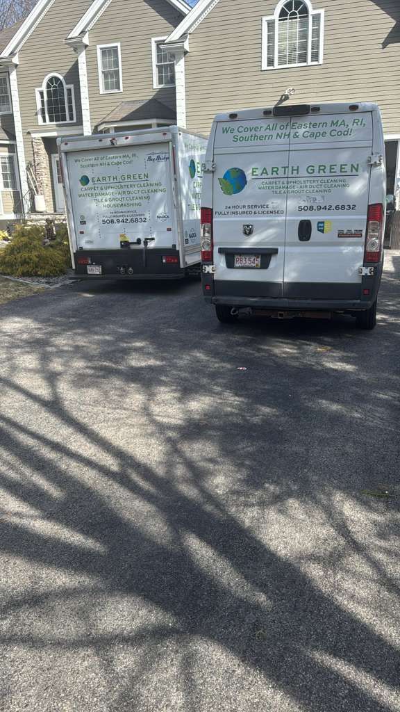 Two white EarthStream vans are parked in a driveway in front of a house.