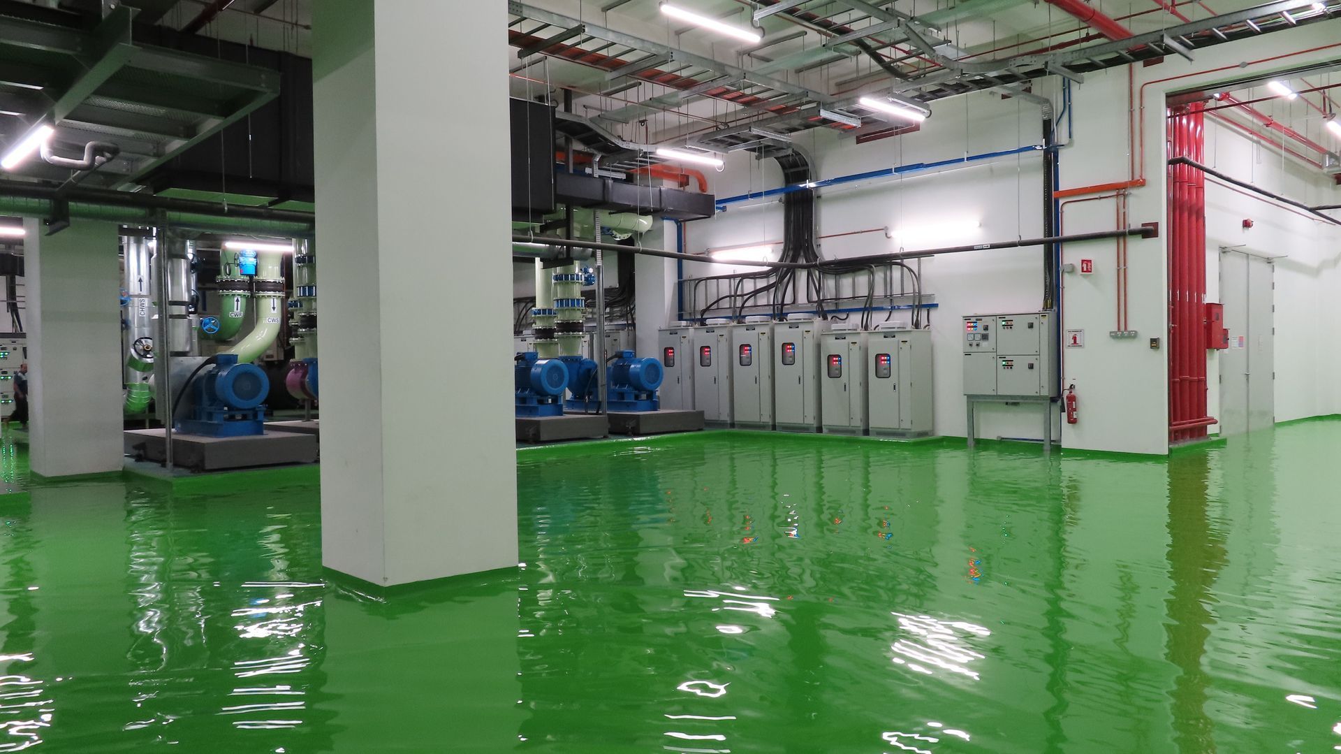 Water damage restoration for industrial plant interior with large blue machinery and electrical panels.