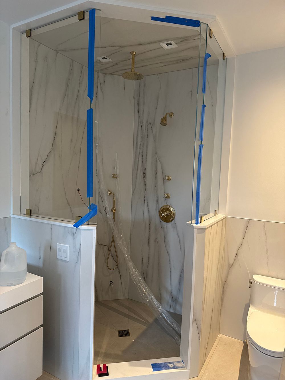 Tiled shower stall under renovation, with plastic sheeting and blue painter’s tape covering the opening.