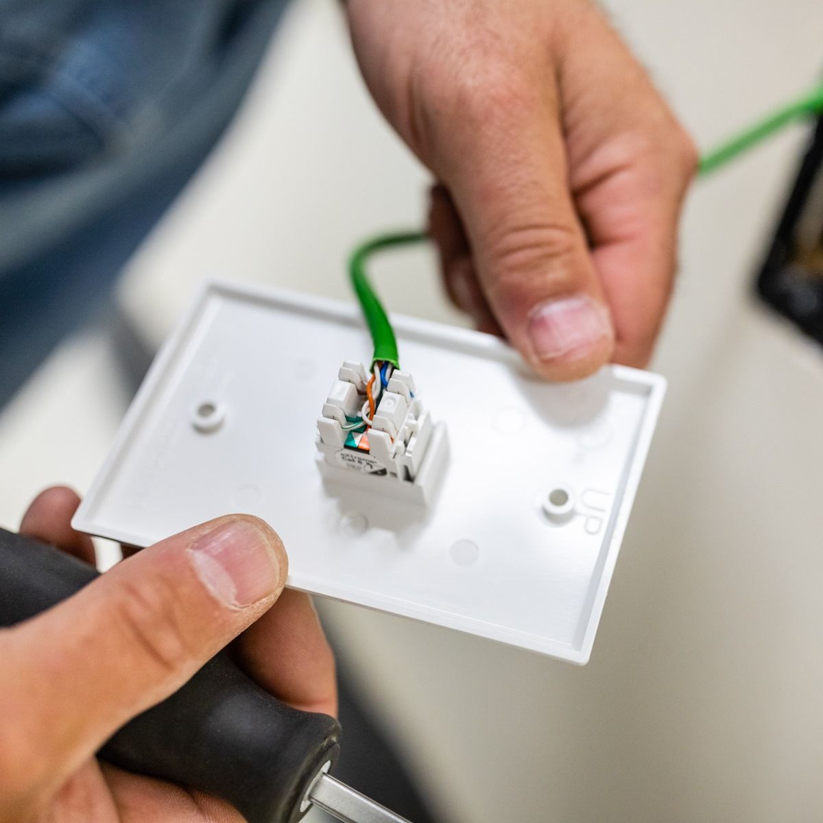A person is holding a white plate with a green wire coming out of it