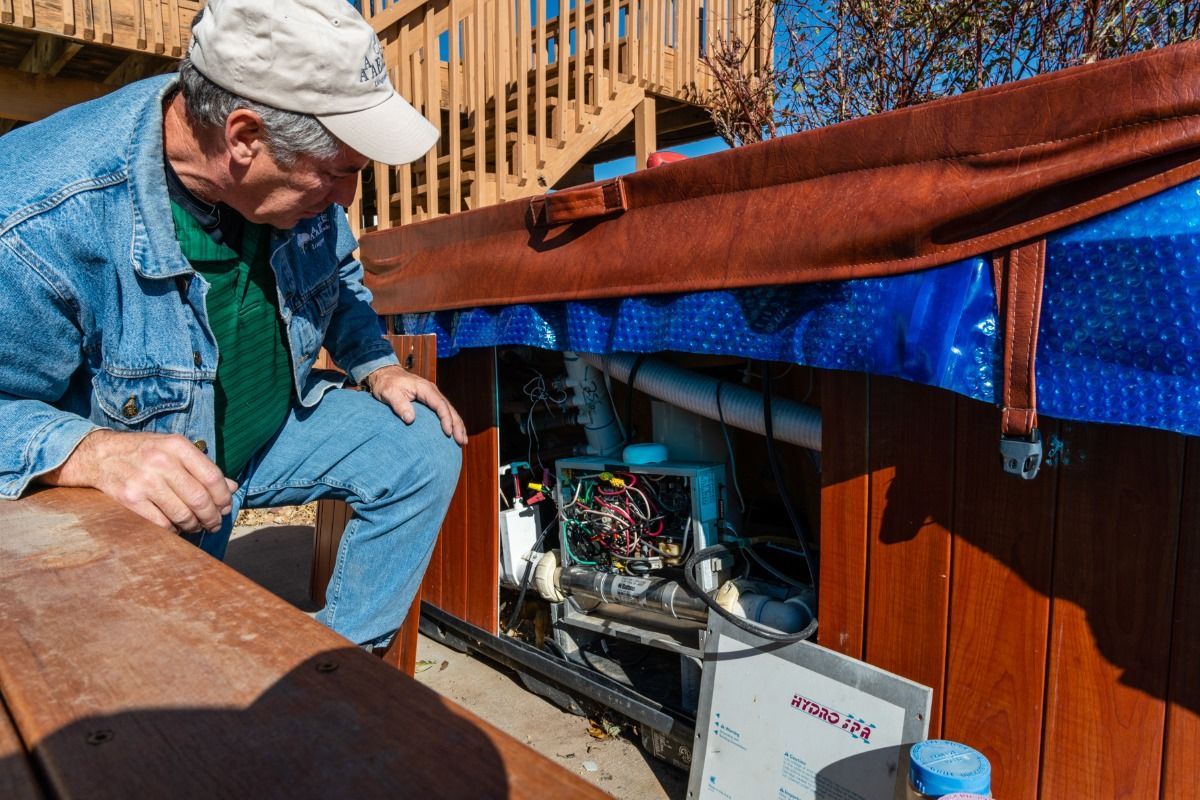 A man is sitting on a bench looking into a hot tub.