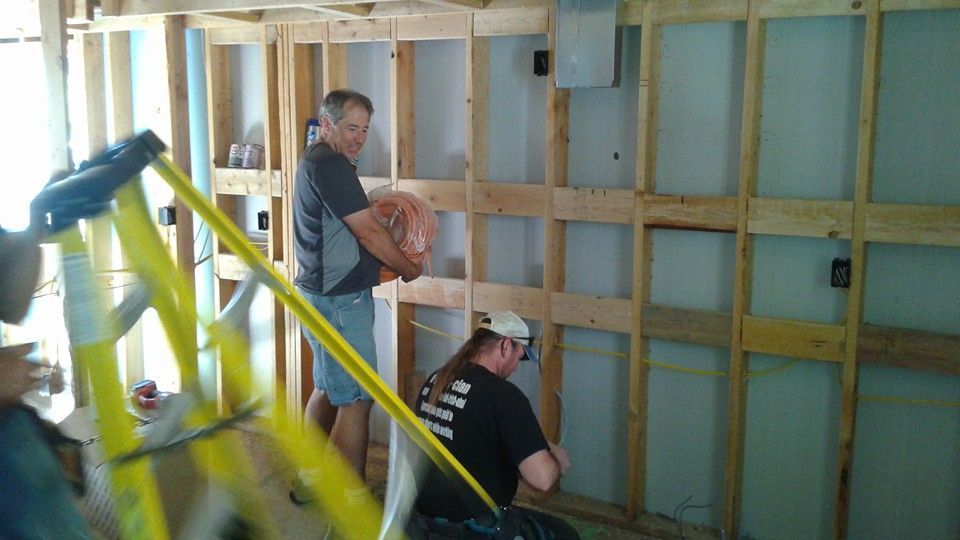 Two men are working on a wall in a room.