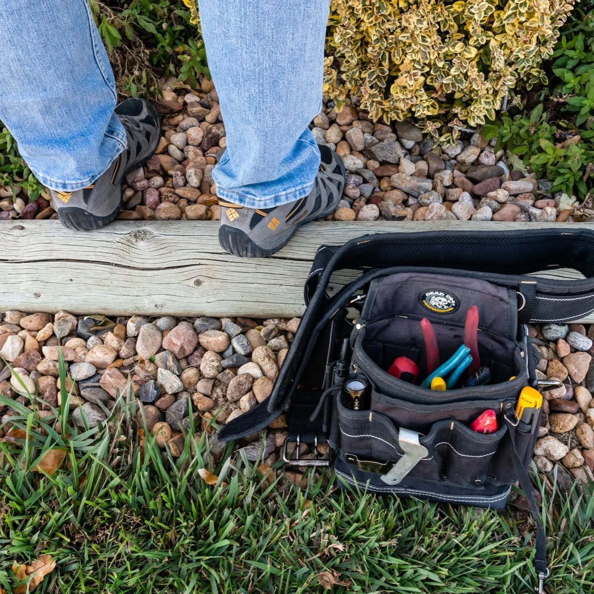 A person standing next to a tool bag filled with tools