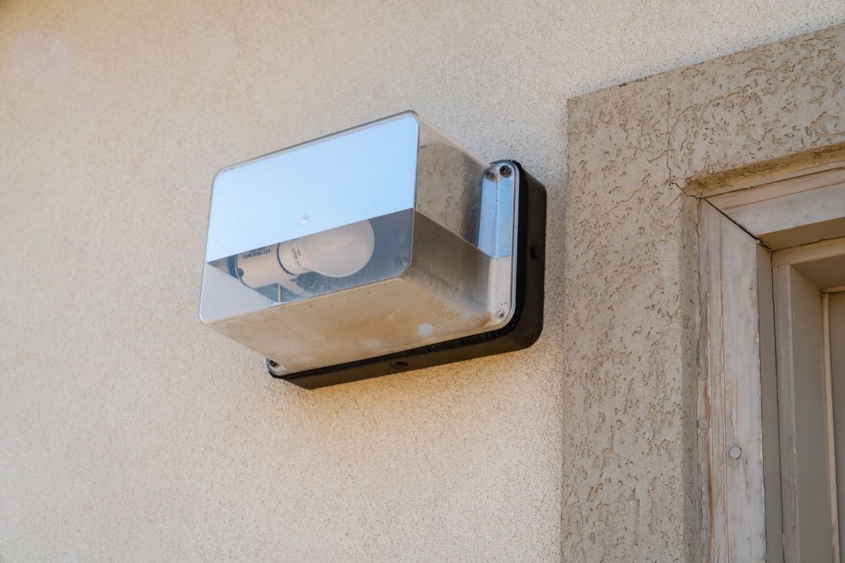 A light on the side of a building next to a window.