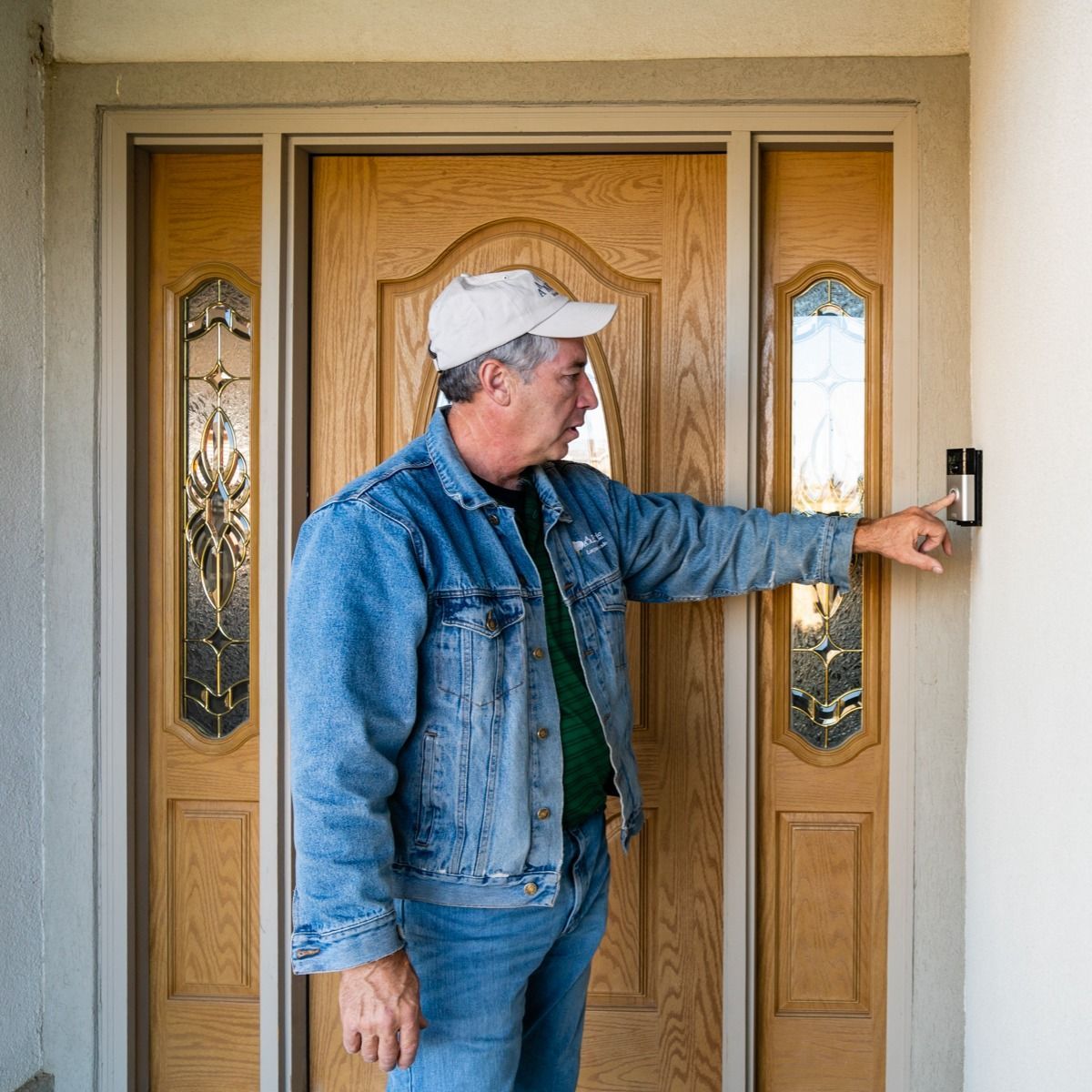 A man in a denim jacket is pressing a button on a door