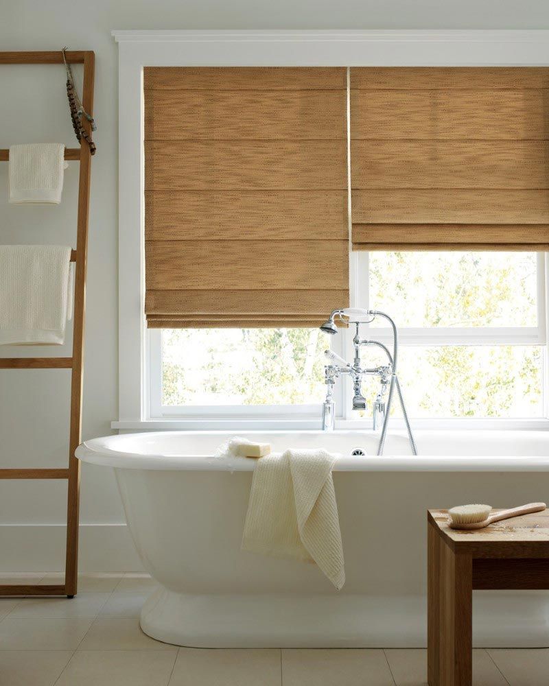 A bathroom with a bathtub and a window with blinds