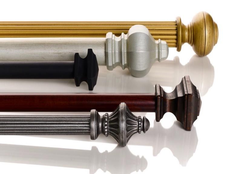 Four different types of curtain poles are lined up on a white surface