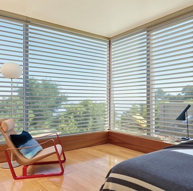 A bedroom with a bed a chair and a lamp