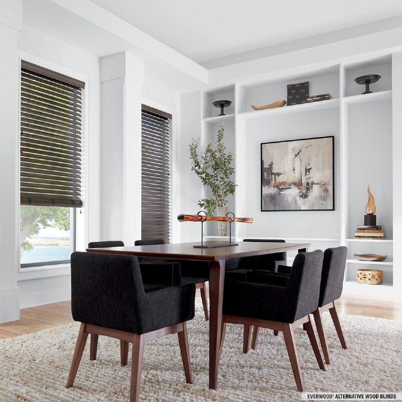 A dining room with a table and chairs and a painting on the wall