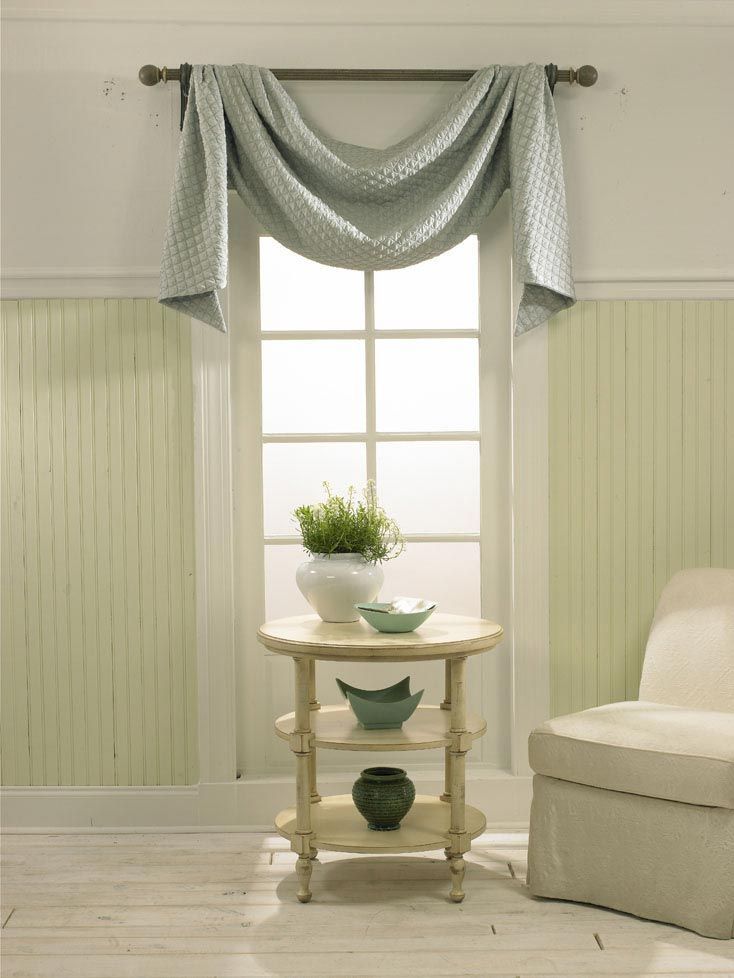 A living room with a table and a chair in front of a window.