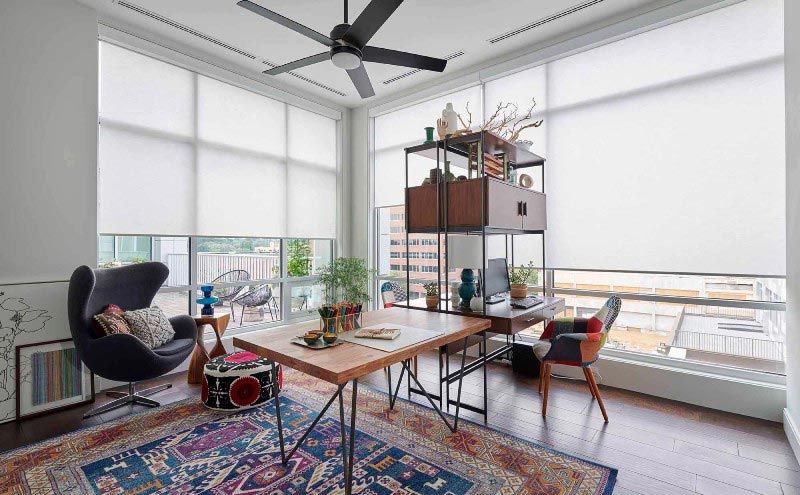 A living room with a table , chair , rug and ceiling fan.