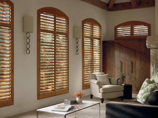 A living room with arched windows and wooden shutters