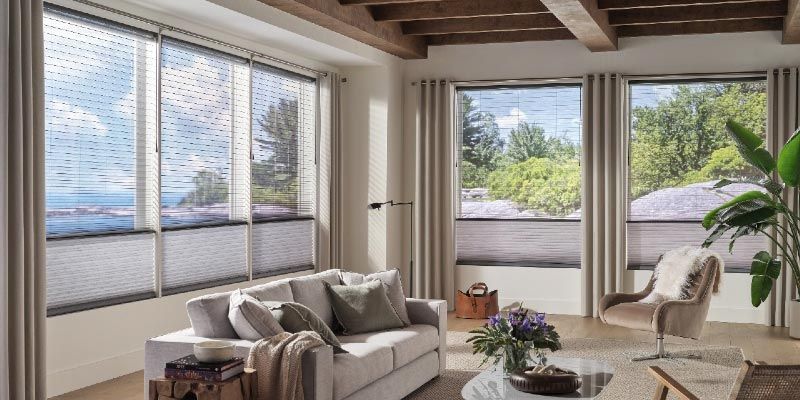 A living room with a couch , chair , table and lots of windows.