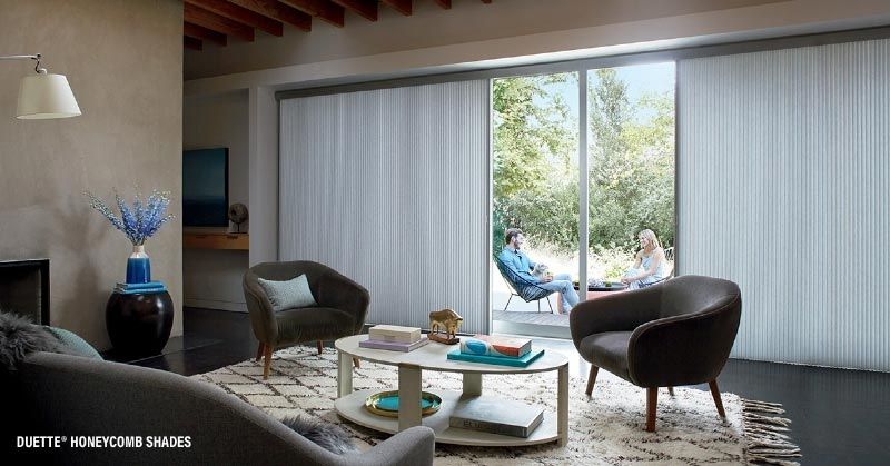 A living room with a couch , chairs , coffee table and sliding glass doors.