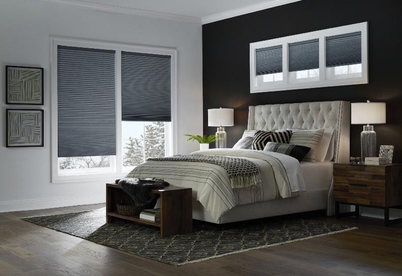 A bedroom with a bed , nightstand , lamps , and black walls.