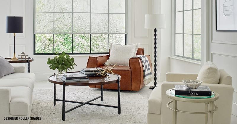 A living room with a couch , chair , coffee table and lamp.