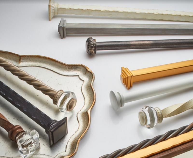 A variety of curtain poles are sitting on a tray on a table.