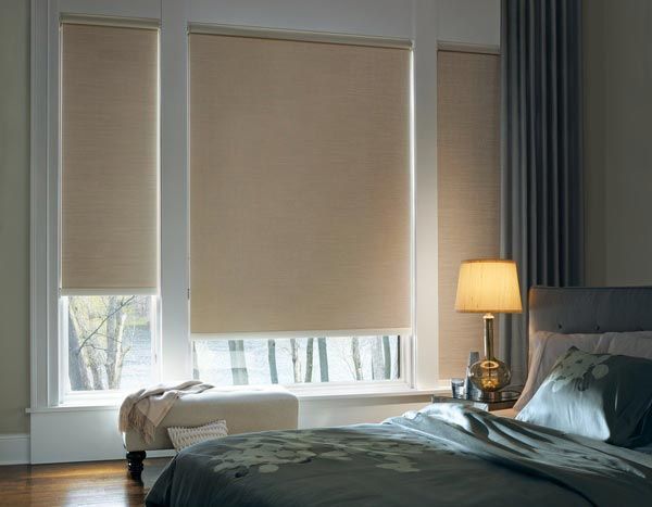 A bedroom with a bed , a lamp , and a window with blinds.