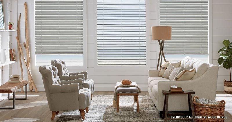 A living room with a couch , chairs , and blinds on the windows.