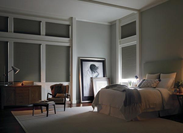 A bedroom with a bed , chair , nightstand , lamp and a picture on the wall.