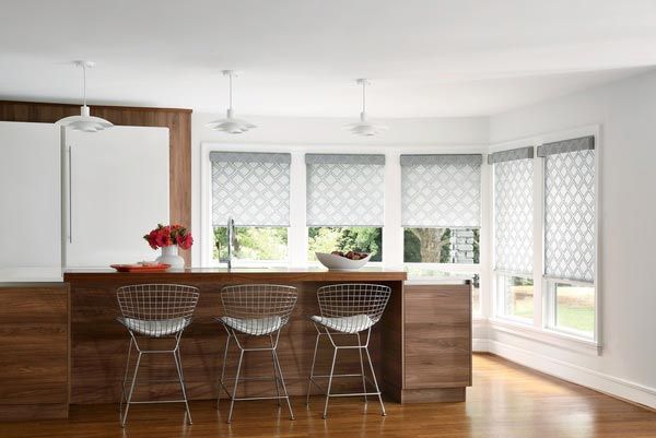 A kitchen with a wooden island , stools , and white blinds.