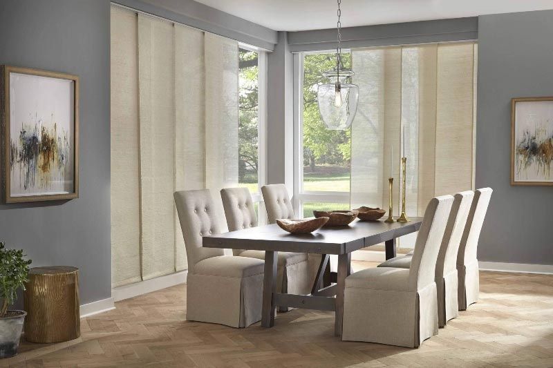 A dining room with a table and chairs and sliding panels on the windows.