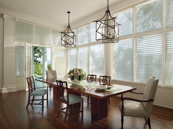 A dining room with a long table and chairs and lots of windows.
