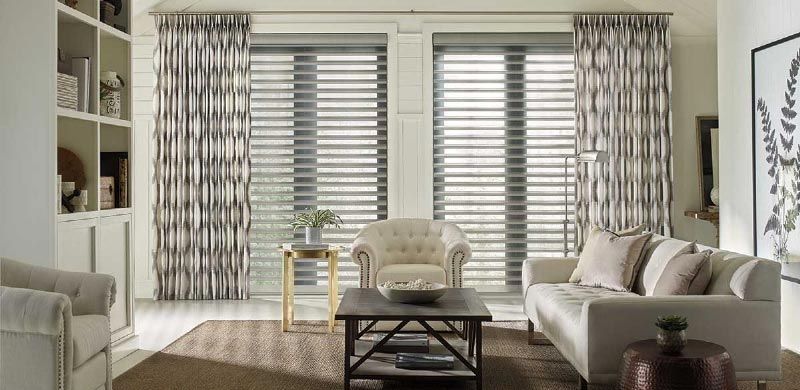 A living room with a couch , chair , coffee table and curtains.