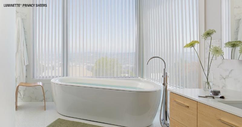 A bathroom with a bathtub , sink , and window.