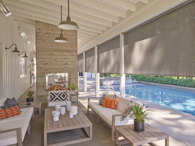 A living room with a couch , table , and fireplace next to a pool.