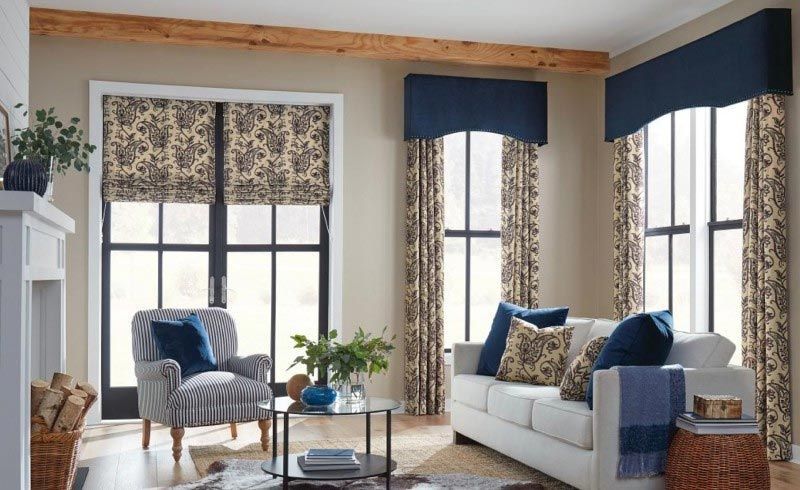 A living room with a couch , chair , coffee table and windows.