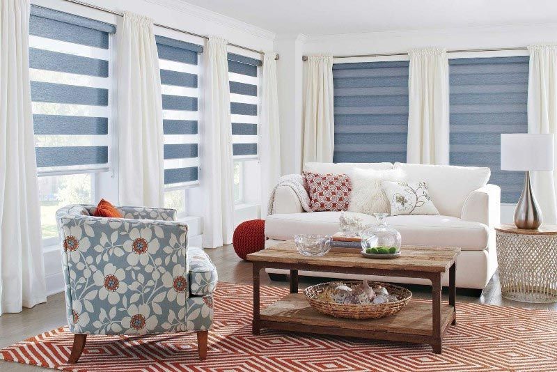 A living room with a couch , chair , coffee table and striped blinds.