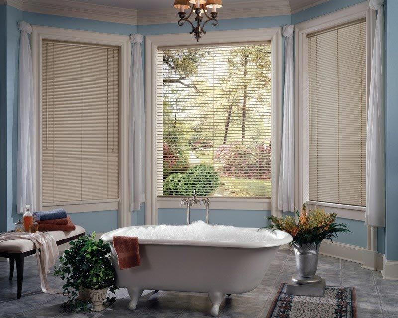 A bathroom with a tub and a window with blinds
